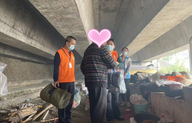 4-6在清远大桥北桥头附近，清远市救助管理站工作人员找到长期住在此的一名流浪人员。多次劝导其进站受助但被拒后，工作人员为他送上棉衣、鞋子、食物等物资_副本.png